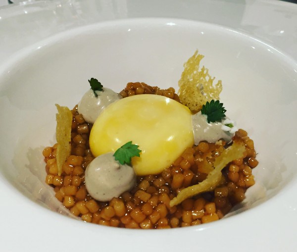 Imagen de un Huevo de caserío, guiso de trigo y jugo de pimientos a la brasa con pan de maíz de Mungia.